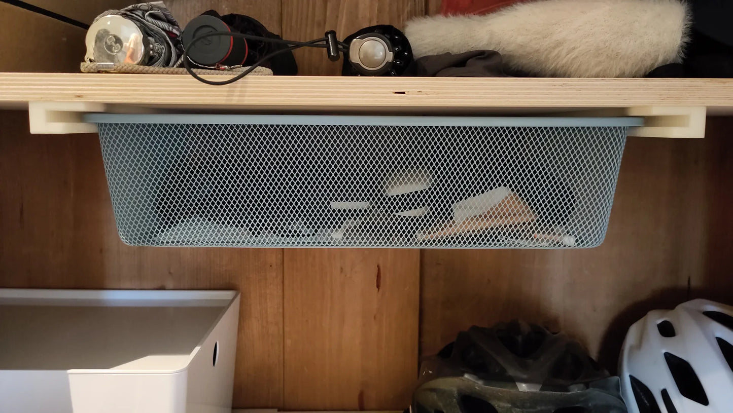 Metal mesh storage basket hanging on a wooden shelf with various items below.