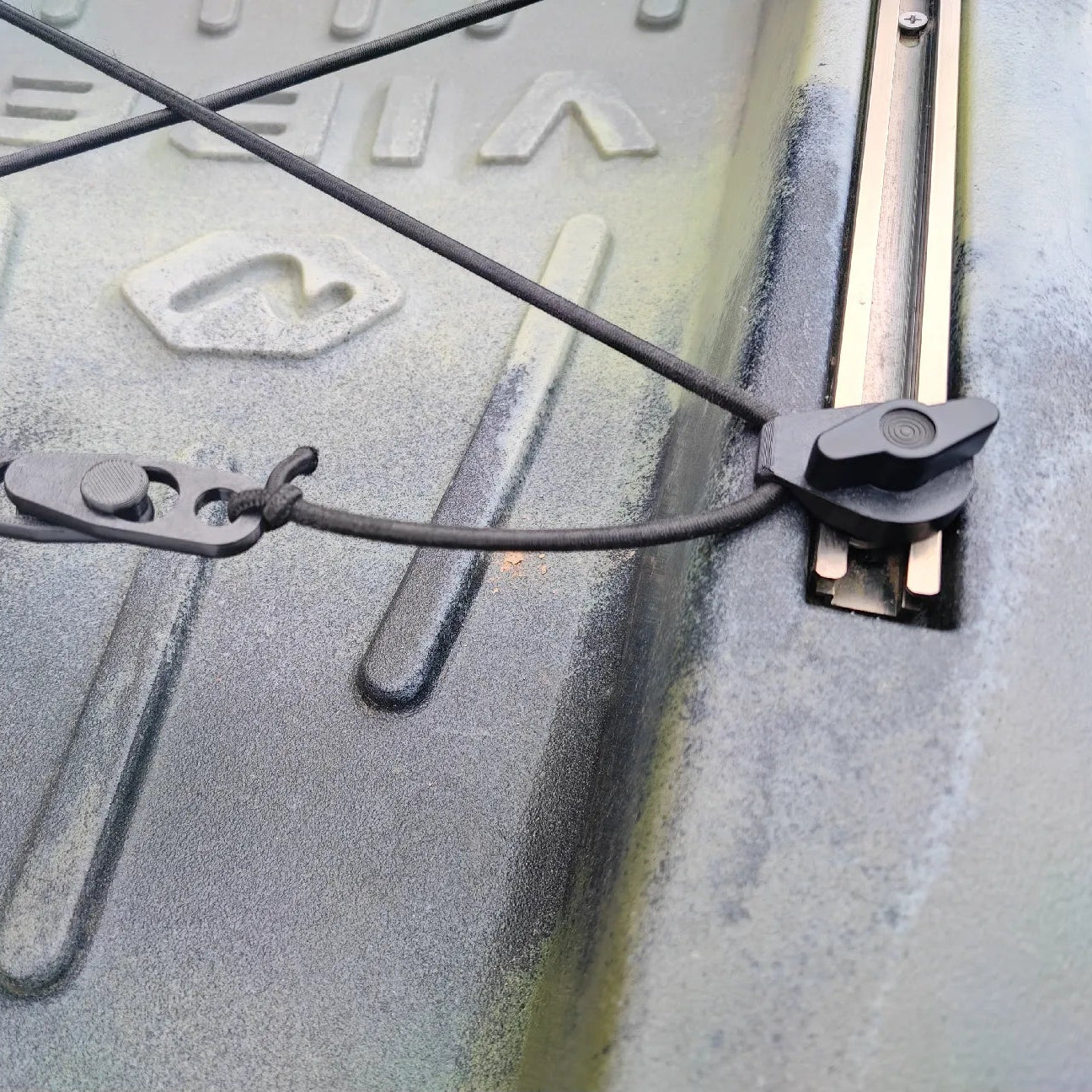 Close-up of a metal surface with engraved text and a clamp, showing signs of wear.