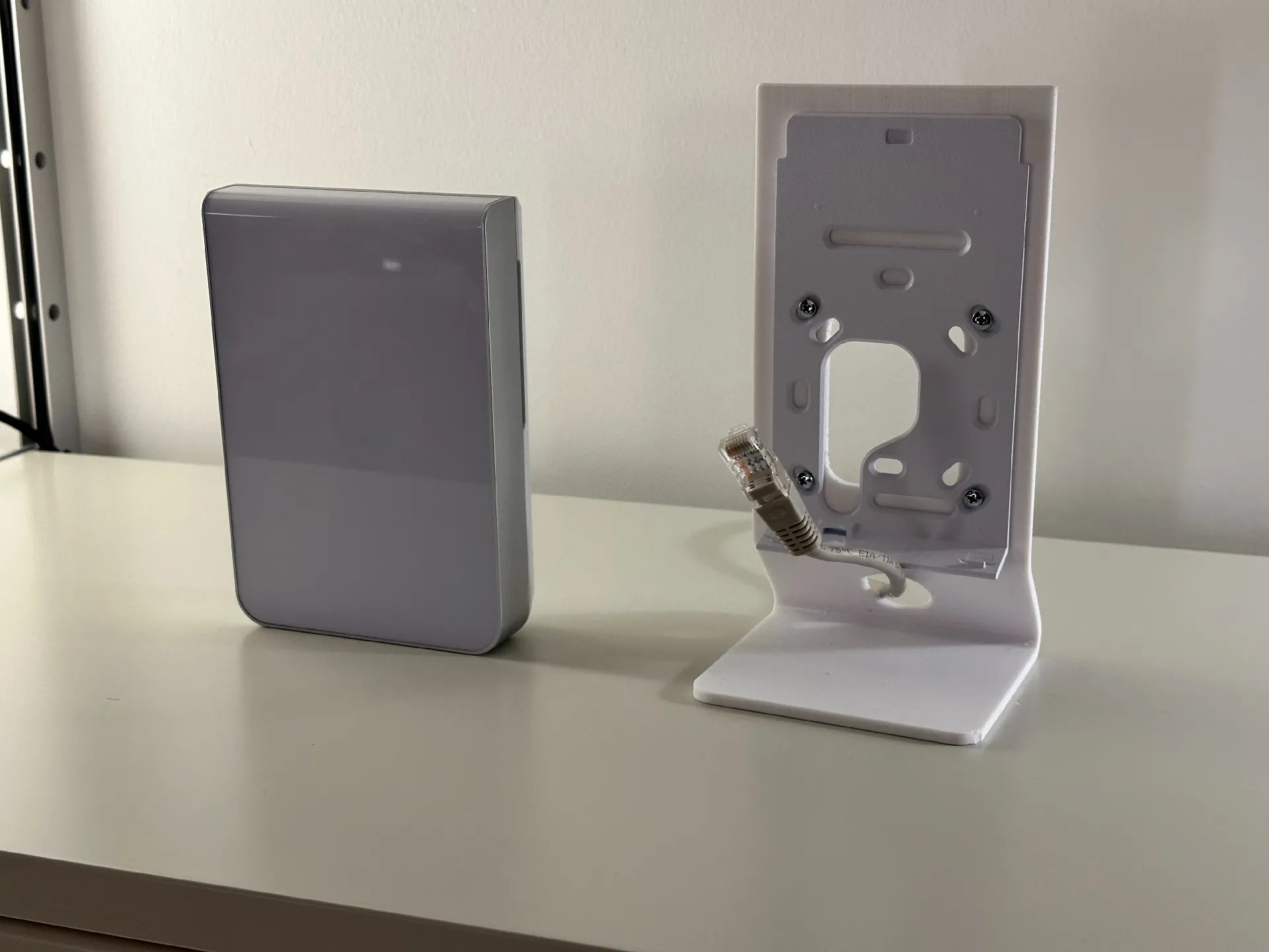 Ubiquiti UniFi U7 Pro Wall sitting on a tech desktop setup alongside a laptop and ethernet cable
