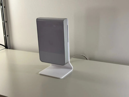 Matte white desk stand holding a Ubiquiti UniFi U7 Pro Wall access point upright on a modern wood office desk