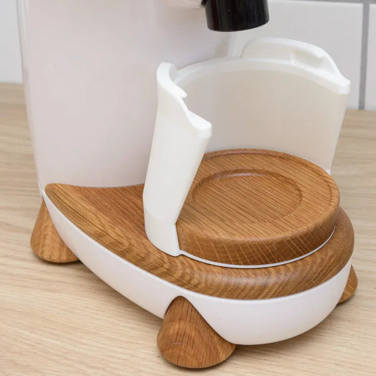 White coffee maker with a wooden base on a wooden surface
